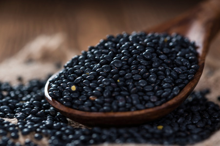 Heap of Black Lentils on wooden background (close-up shot)の写真素材