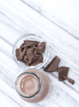 Chocolate Milk in a small bottle (on bright wooden background)の写真素材