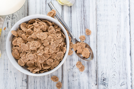 Bowl with Wholemeal Cornflakes (close-up shot) on a wooden table