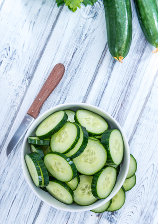 Heap of fresh sliced Cucumbers on an old wooden tableの写真素材