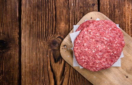 Some fresh made Burgers (raw minced Beef) on an old wooden tableの写真素材