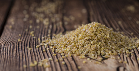 Portion of raw Bulgur (close-up shot) on wooden backgroundの写真素材