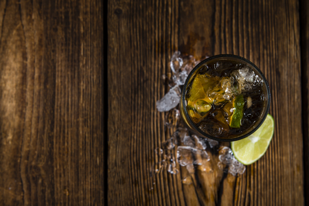 Cold Longdrink (Cuba Libre) with brown rum and fresh lime on rustic wooden backgroundの写真素材