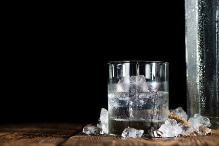 Vodka on the rocks on an old wooden table as detailed close-up shot