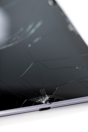 A broken tablet computer as detailed close-up shot on neutral white backgroundの写真素材