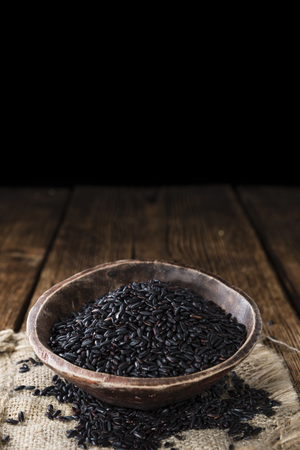 Heap of Black Rice (close-up shot) on an old wooden tableの写真素材
