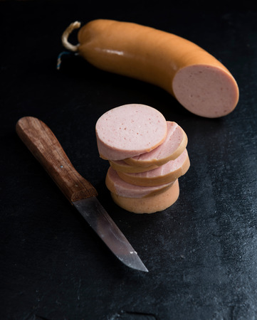 Sliced Sausage (Baloney) on an old wooden table (close-up shot)の写真素材