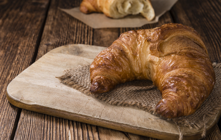 Fresh baked Croissants (close-up shot) on vintage wooden backgroundの写真素材
