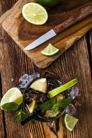 Cold Longdrink (Cuba Libre) with brown rum and fresh lime on rustic wooden backgroundの写真素材