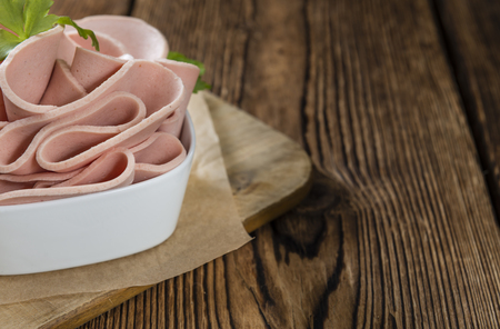 Mortadella Slices (selective focus) on an old wooden tableの写真素材
