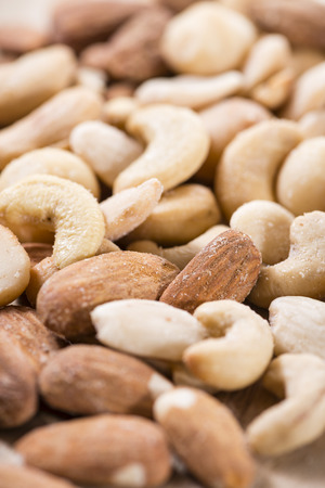 Portion of mixed nuts (roasted and salted) on an old wooden table (selective focus)の写真素材