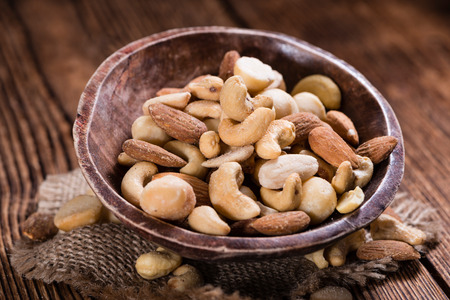 Roasted and salted nuts (mixed) on an old wooden tableの写真素材