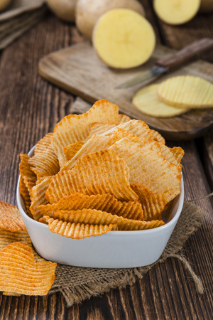 Bowl with rippled Potato Chips (selective focus) on wooden backgroundの写真素材
