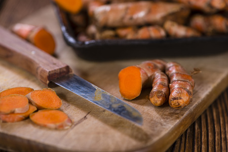 Some fresh Turmeric on an old wooden table (detailed close-up shot, selective focus)の写真素材