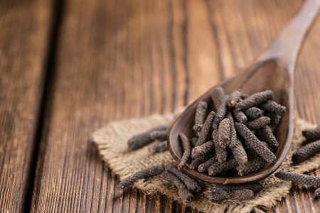 Heap of long Pepper (selective focus) on wooden background (close-up shot)の写真素材