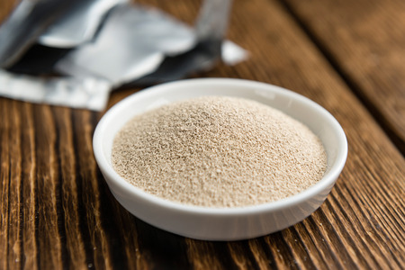Bowl with dried Yeast (selective focus) on wooden backgroundの写真素材