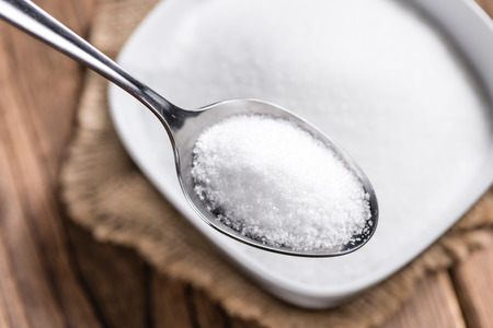 Portion of White Sugar (detailed close-up shot; selective focus) on wooden backgroundの写真素材