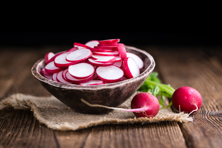 Radishes (chopped) on an old wooden table (selective focus, close-up shot)の写真素材