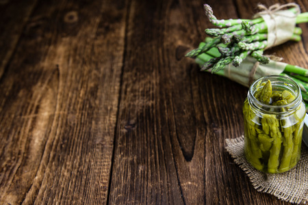 Green Asparagus (preserved) on an old wooden table (selective focus)の写真素材