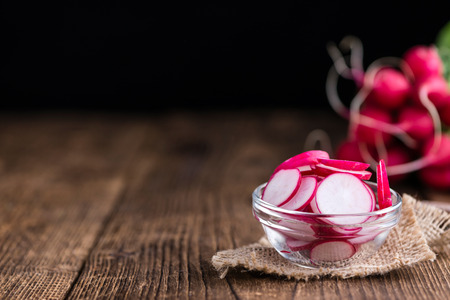 Radishes (chopped) on an old wooden table (selective focus, close-up shot)の写真素材