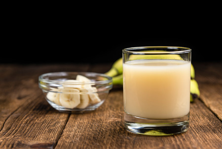 Fresh made Banana Juice (selective focus) on an old wooden tableの写真素材