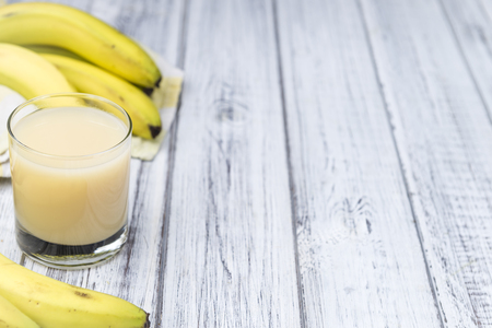 Glass of Banana Juice (close-up shot) on wooden backgroundの写真素材