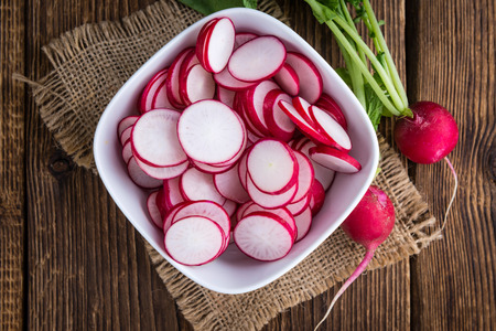 Radishes (chopped) on an old wooden table (selective focus, close-up shot)の写真素材