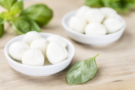 Small Mozzarella balls (on wooden background; selective focus) as close-up shotの写真素材