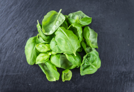 Portion of fresh Basil (close-up shot; selective focus) on a slate slabの写真素材