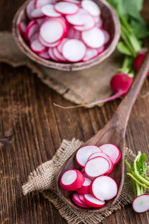 Some fresh chopped Radishes (close-up shot) on wooden backgroundの写真素材
