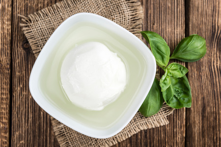 Portion of fresh Mozzarella (close-up shot) on wooden background (selective focus)の写真素材