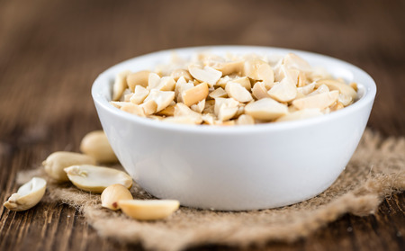Portion of chopped Peanuts (close-up shot; selective focus) on wooden background