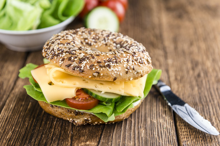 Bagel with Cheese (Gouda) and some fresh vegetables (close-up shot; selective focus)の写真素材