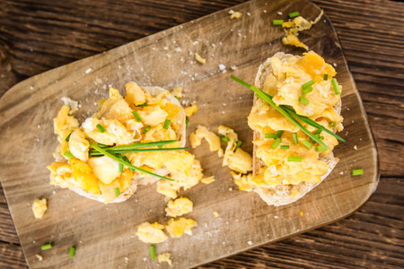 Scrambled Eggs on a bun (close-up shot; selective focus) on vintage background