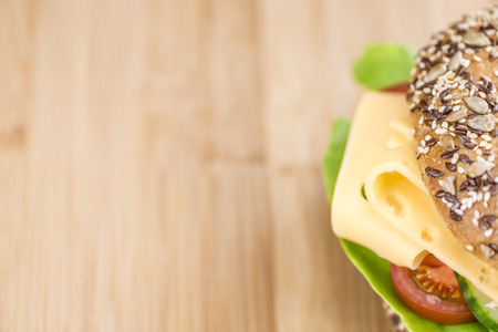 Bagel with Cheese (Gouda) and some fresh vegetables (close-up shot; selective focus)