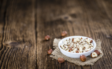 Portion of chopped Hazelnuts on wooden background (close-up shot; selective focus)の写真素材