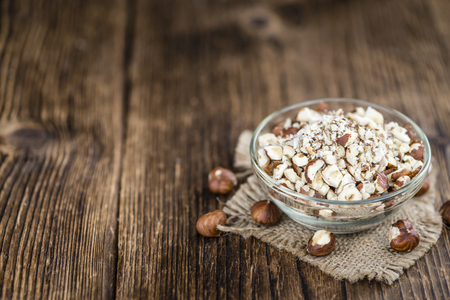 Portion of chopped Hazelnuts on wooden background (close-up shot; selective focus)の写真素材