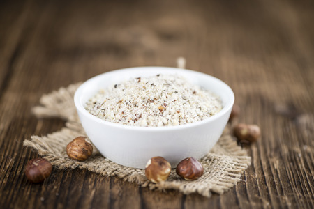 Wooden table with grounded Hazelnuts (close-up shot; selective focus)の写真素材