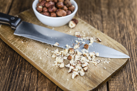 Wooden table with chopped Hazelnuts (selective focus; close-up shot)の写真素材