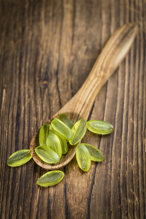 Heap of gummy candy with lime taste on wooden background (selective focus; close-up shot)の写真素材