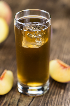 Ice Tea (Peach) on an old wooden table (selective focus; close-up shot)の写真素材