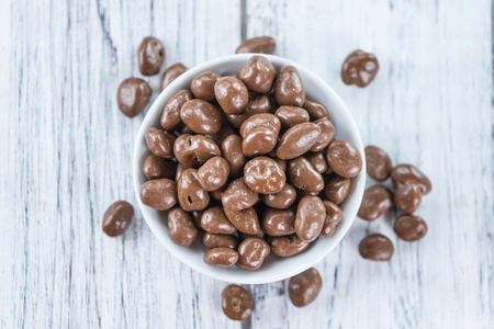 Old wooden table with Chocolate Raisins (close-up shot)