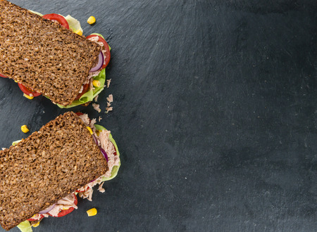 Slate slab with a Tuna Sandwich (wholemeal bread; selective focus; close-up shot)の写真素材