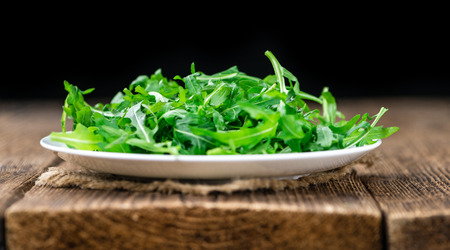 Wooden table with fresh Arugula as detailed close-up shot (selective focus)の写真素材