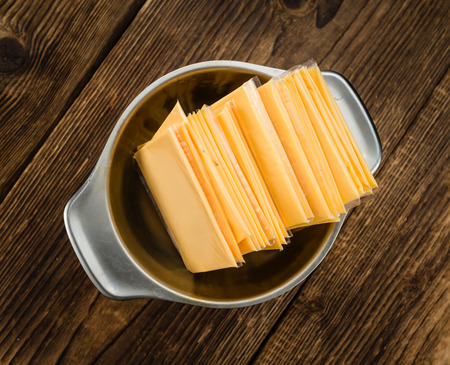 Cheese (sliced) on an old wooden table as detailed close-up shot (selective focus)の写真素材