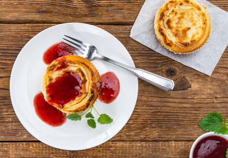 Mini Cheesecake (with Sauce) as high detailed close-up shot on a vintage wooden table (selective focus)の写真素材