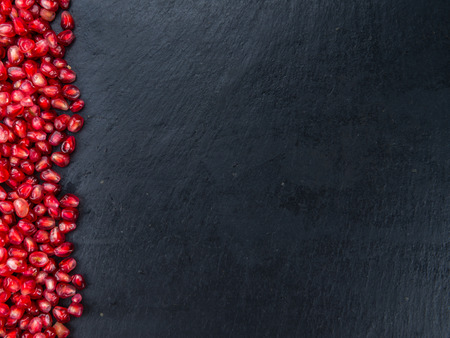 Portion of Pomegranate as detailed close up shot on a slate slab (selective focus)の写真素材
