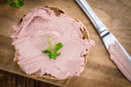 Roll with Liverwurst (German cuisine) on an old wooden table as detailed close-up shot (selective focus)の写真素材