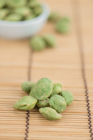 Peanuts (with Wasabi flavor) on an old wooden table as detailed close-up shot (selective focus)の写真素材