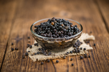 Preserved black Peppercorns on a wooden table as close-up shotの写真素材